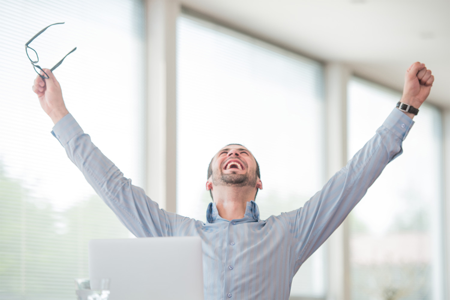 Picture of a man celebrating with his arms lifted in the air representing the happy clients that saved money by breaking their mortgage